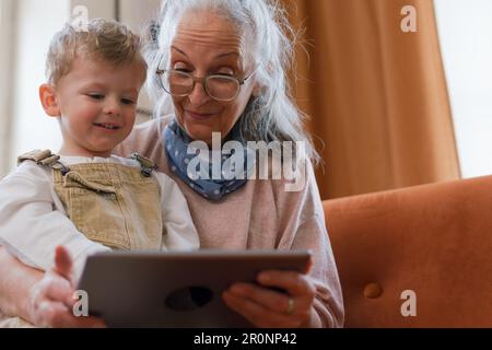 Grandmother looking fairytale with her grandson on digital tablet. Stock Photo
