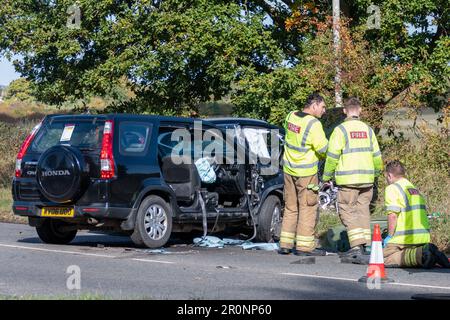 Chippenham Wiltshire UK, 10 October 2023. Firecrew clearing up after a road traffic collision with cars showing impact damage and removed doors for re Stock Photo