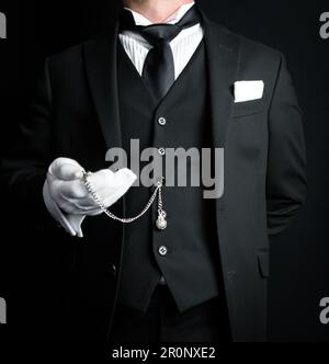 Portrait of Formal Butler in Dark Suit and White Gloves Holding Pocket Watch. Service Industry and Professional Hospitality. Stock Photo