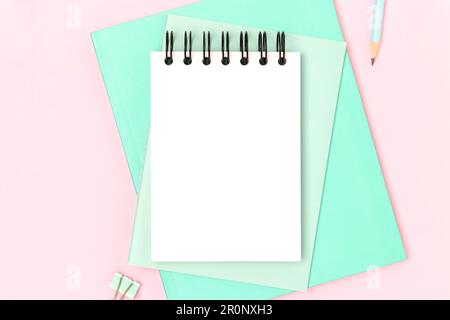 Workspace with empty notepad mock up and mint colored stationery on a pink background. Place for text. Stock Photo