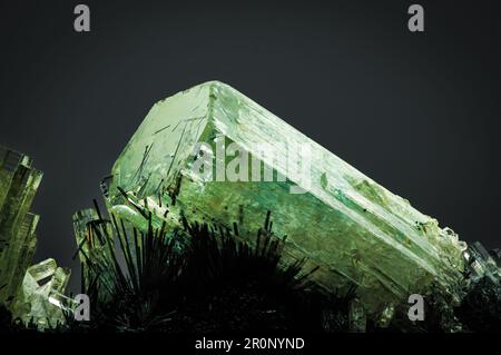 green beryl (emerald) on schorl (black tourmaline) matrix. macro detail texture background. close-up raw rough unpolished semi-precious gemstone with Stock Photo