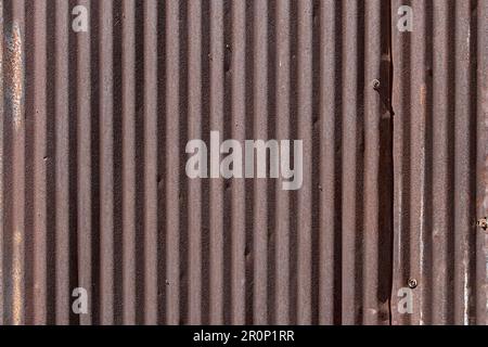 A view of old rusty sheet metal surface with corrugated texture, as a background. Stock Photo