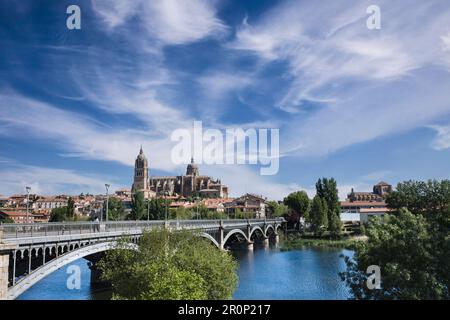 Perspective view of the bridge of Enrique Estevan over the Tormes river and the cathedral of Salamanca in the background with blue sky and light white Stock Photo