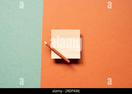 Blank memo pad brown kraft paper with colored pencil isolated on green and red background. top view, copy space Stock Photo