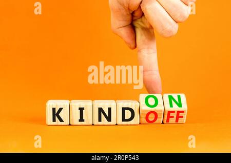 Kind on or off symbol. Businessman turns wooden cubes and changes word Kind off to Kind on. Beautiful orange table orange background. Business and kin Stock Photo