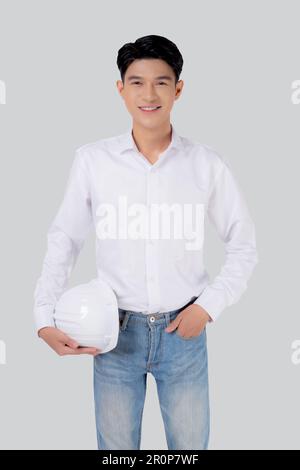 Portrait young asian man is engineer holding helmet standing and smiling with confident isolated on white background, handsome male is architect or co Stock Photo