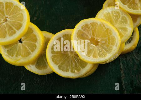 whole and sliced lemons arranged in a circular pattern on a green painted rustic peeling old table Stock Photo