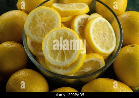 whole and sliced lemons arranged in a circular pattern on a green painted rustic peeling old table Stock Photo