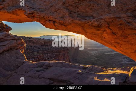 Sunrise over the La Sal Mountains seen through Mesa Arch in Canyonlands National Park near Moab, Utah. Stock Photo