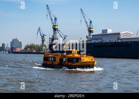 Hamburg, Germany - 04 17 2023: view from the water on a ferry on the elbe in hamburg with a dock and the elbphiharmonie in the background. Stock Photo