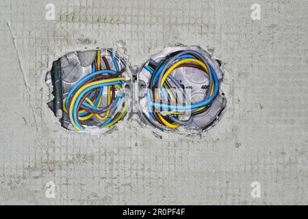 Boxes with cables for electric sockets installed in new house building empty wall with fibre textile mesh layer applied Stock Photo