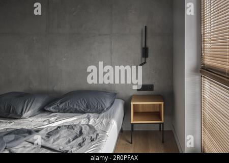 Minimalistic black wall light in modern bedroom interior in grey and black colours, concrete wall design, clay wall. Contemporary interior design aest Stock Photo