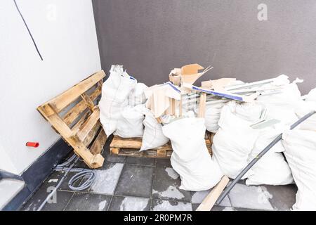 construction debris on the street near a house . Wooden window frame and bags of cement, sand and garbage. The concept of construction and repair in Stock Photo