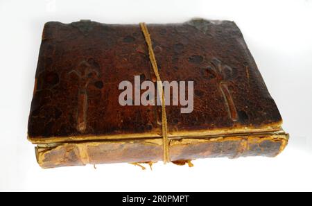 Old weathered book with leather cover and loose spine. It is held together by a leather cord. The background is white Stock Photo