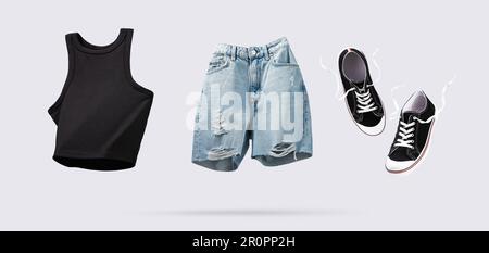 Trendy flying cotton tank top, blue jeans shorts and sneakers isolated on gray background. Clean black crop top. Branding clothes. Mock up for your de Stock Photo