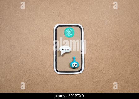 Mobile phone made of paper with bot in the speech bubble on the display, concept of chatting with bot. Asking question to AI. Cardboard smartphone wit Stock Photo