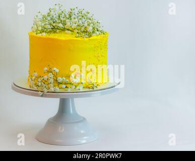 studio shot of yellow celebration frosted cup cake with wild white flowers isolated on white background Stock Photo