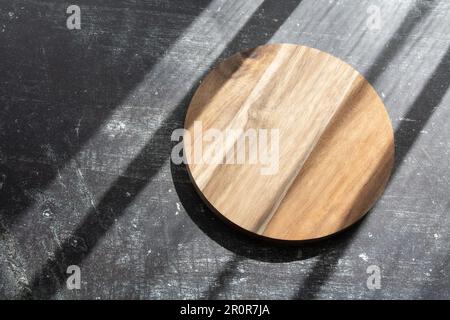photo round cutting board on a table on a dark table, shade from the sun Stock Photo