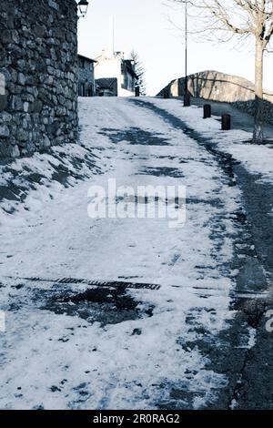 Snowy cobble stone paved road covered with ice and snow in a townscape winter scene in Bellver de Cerdanya Stock Photo
