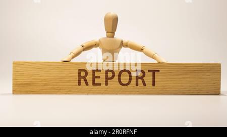 Report text written on wooden surface. wooden man. Stock Photo