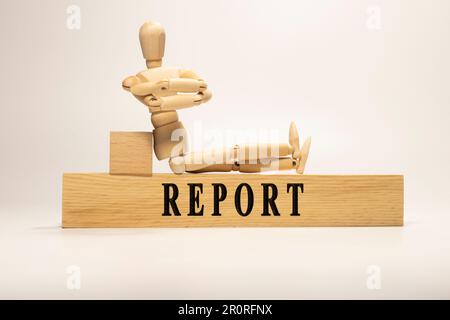 Report text written on wooden surface. wooden man. Stock Photo