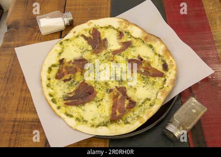 Large thin crust pizza with prosciutto, pesto sauce and mozzarella cheese Stock Photo