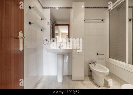 A complete bathroom with showers with screens, white column furniture and a rectangular mirror over the sin Stock Photo