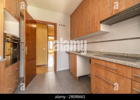 Furnished kitchen of a home with cherry-colored wood cabinets and polished gray granite countertops Stock Photo