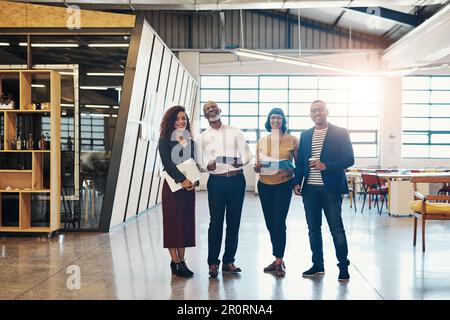 Success is about the attitude you have as a team. Portrait of a group of designers standing together in an office. Stock Photo