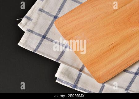 Wood Tray with striped fabric on black background.Empty wooden serving board with napkin on a dark background. Stock Photo
