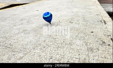 Blue spinning top, toy for children and adults, a type of spinning top that can rotate on one end, its gravitational center with a gyroscopic effect Stock Photo