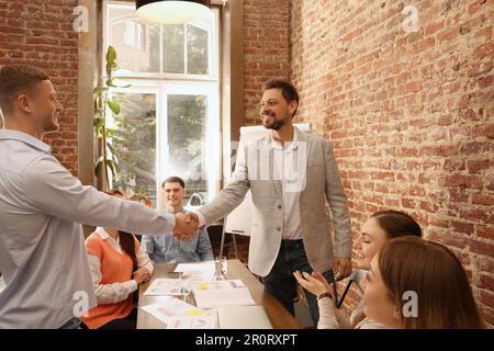 Office employees shaking hands during meeting at work Stock Photo