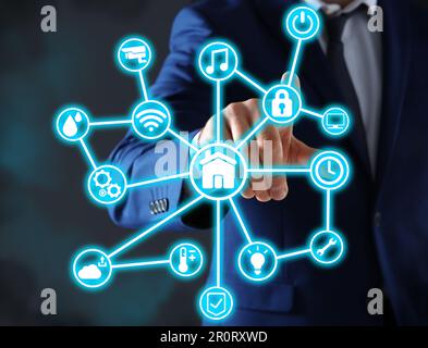 Man using digital screen with Smart Home interface on dark background, closeup Stock Photo