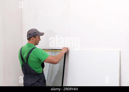 Worker in uniform measuring double glazing window indoors Stock Photo
