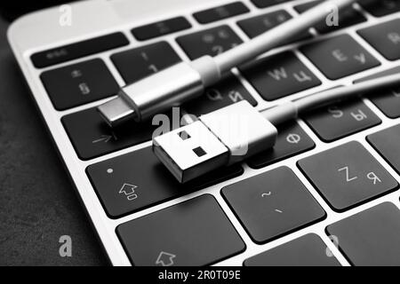 USB cable with type C connector and laptop on dark table, closeup Stock Photo