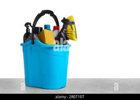 Bucket with many different car wash products on grey table against white background Stock Photo