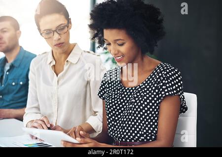 Making great progress on their latest project. two colleagues discussing something on a digital tablet together. Stock Photo