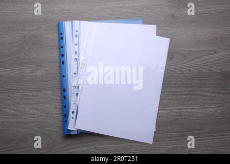 File folder with punched pockets and paper sheets on wooden table, top view Stock Photo