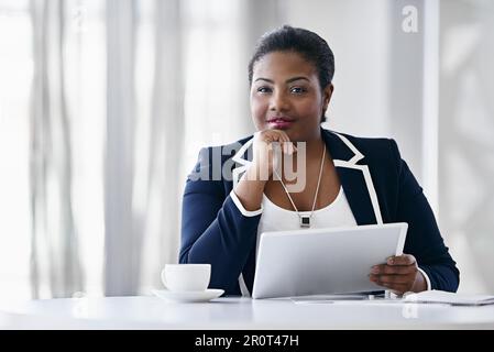 Shes making her own success. Portrait of a young businesswoman using a digital tablet while sitting at a desk in an office. Stock Photo