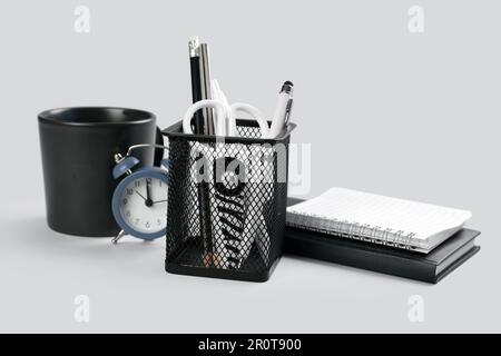Stationery holder, notebooks and alarm on grey background Stock Photo