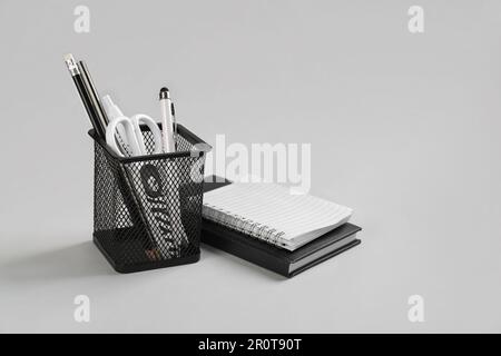 Stationery holder and notebooks on grey background Stock Photo