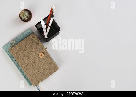 Stationery holder, notebooks and cactus on grey background Stock Photo