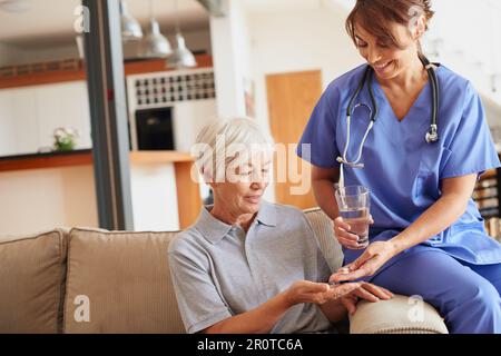 Take these twice daily after meals. a female doctor giving medication to a senior patient. Stock Photo