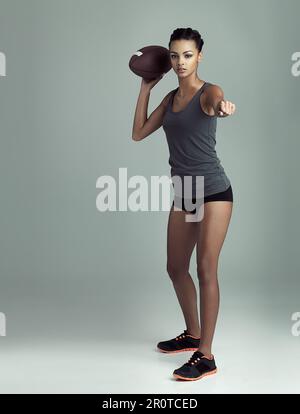 Go long. Studio shot of a fit young football player against a gray background. Stock Photo