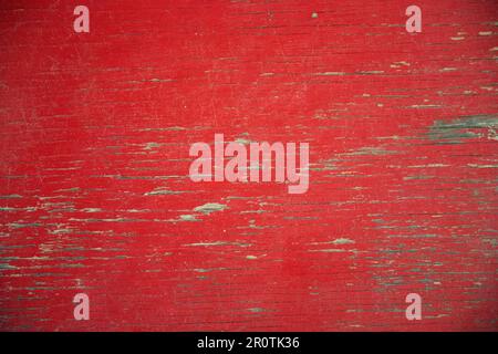 close up of old red painted board with flaking weathered paint and exposed wood grain Stock Photo