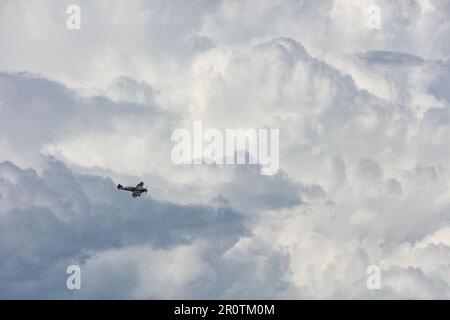 Superrmarine Spitfire (two seat passenger carrying)  turns to land at Biggin Hill with dramatic cumulonimbus thunder clouds on a sunny day Stock Photo