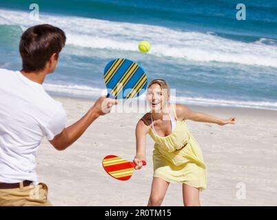 Sun, sand and paddle ball. a happy young couple enjoying a game of paddle ball at the beach. Stock Photo
