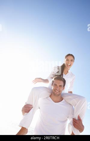 Together theyre unbeatable. a young man carrying his girlfriend on his shoulders. Stock Photo