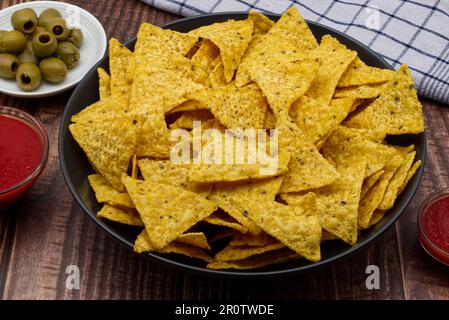 Nachos in a black bowl. Tortilla chips on wooden background. Stock Photo