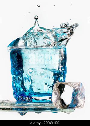 Ice cube falling in a glass of water Stock Photo